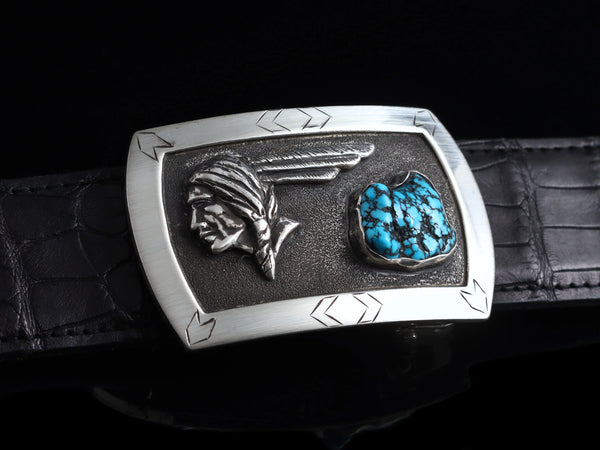 Belt buckle with brushed Sterling silver border holds small arrow engraving as it frames a dark stippled center. The focal points of this buckle are the Sterling silver Pontiac Indian figure and a piece of Kingman Turquoise.