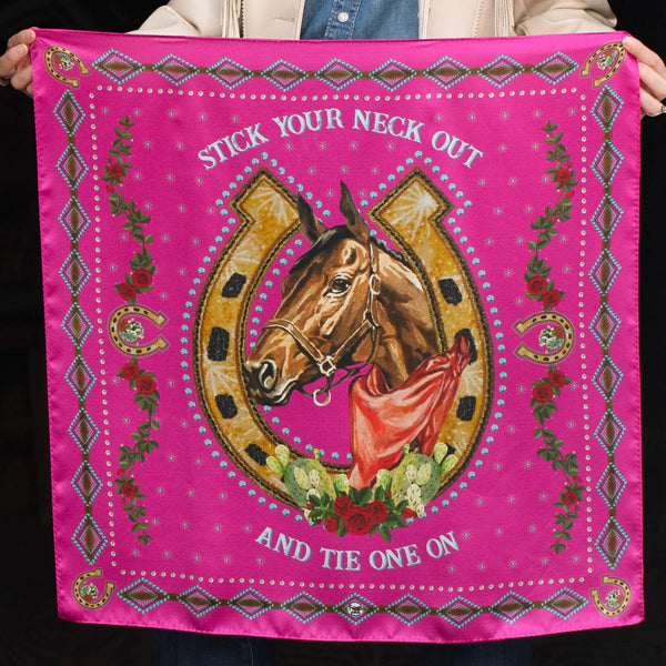 Pink wild rag with horse framed by a shorse shoe in the center with words "Stick Your Neck Out And Tie One On" .