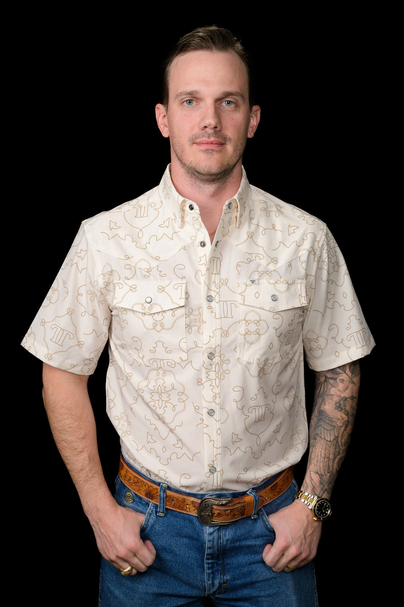 Man wearing a patterned beige shirt and blue jeans on a black background