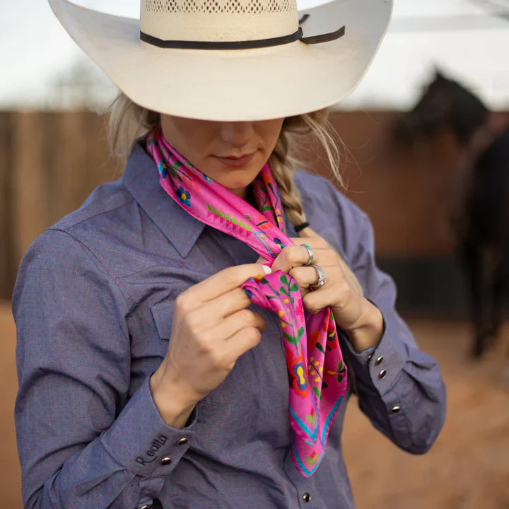 Person wearing a cowboy hat and holding a colorful scarf with a blurred background