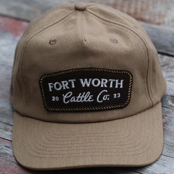 Brown cap with 'Fort Worth Cattle Co.' patch on a wooden surface
