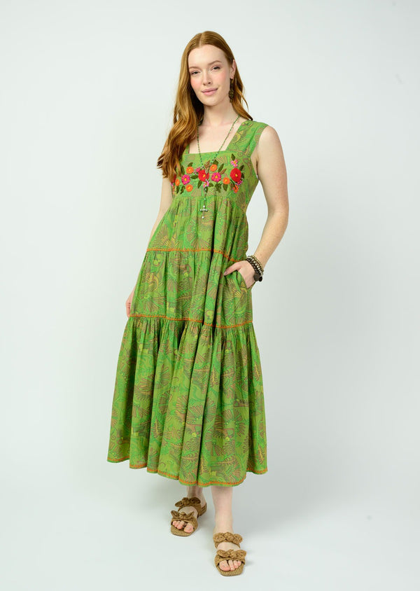 Woman wearing a green dress with floral embroidery on a white background