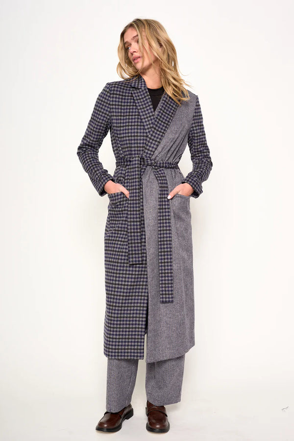 Woman wearing a long, checkered coat on a white background