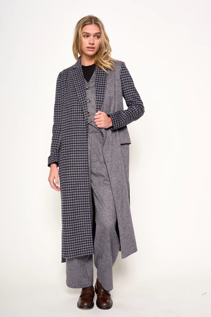 Person wearing a long gray coat with a plaid pattern on a white background