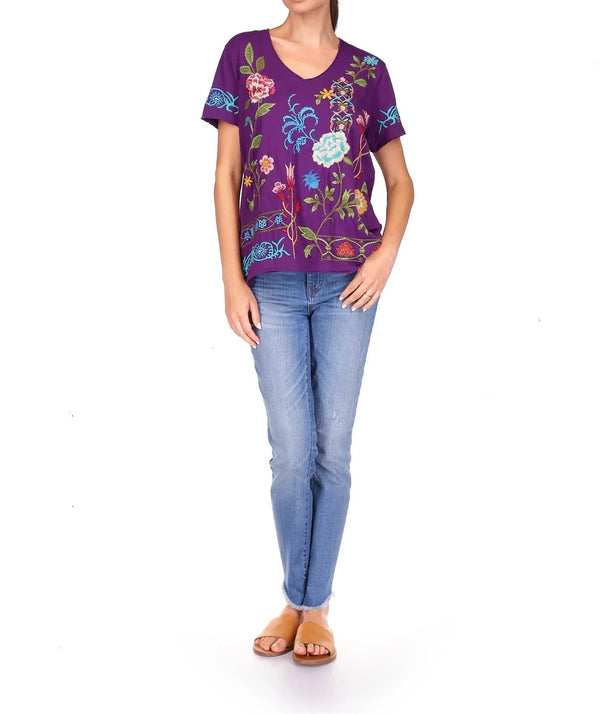Woman wearing purple short sleeve shirt with v-neck and embroidered floral pattern all over