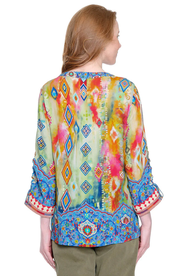 Woman wearing a colorful patterned blouse with a white background