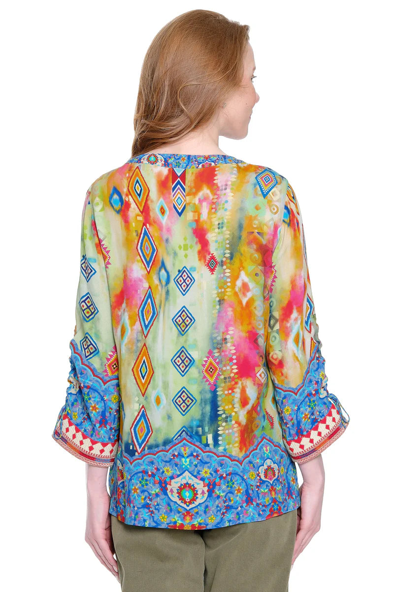 Woman wearing a colorful patterned blouse with a white background