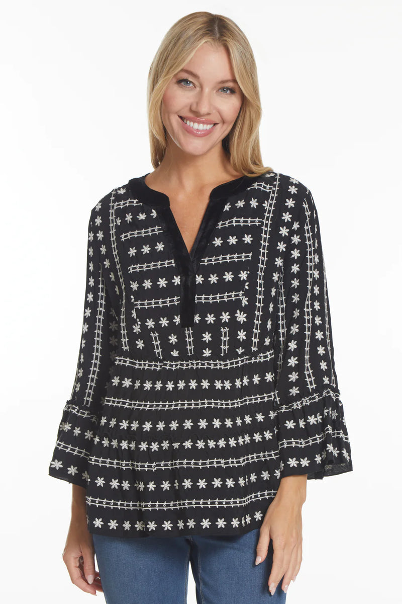 Woman wearing black split neck tunic blouse with white embroidered flowers