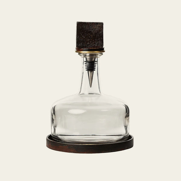 Glass decanter with cast iron base with cast iron cube on the top 