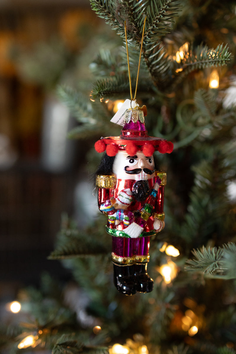 Mexican nutcracker Christmas ornament holding colorful Pinata hanging on Christmas tree