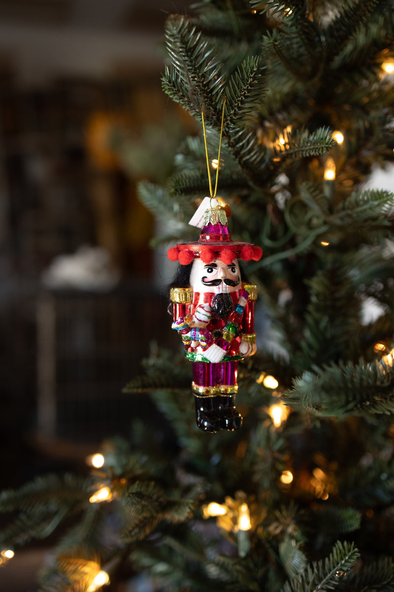 Mexican nutcracker Christmas ornament holding colorful Pinata hanging on Christmas tree