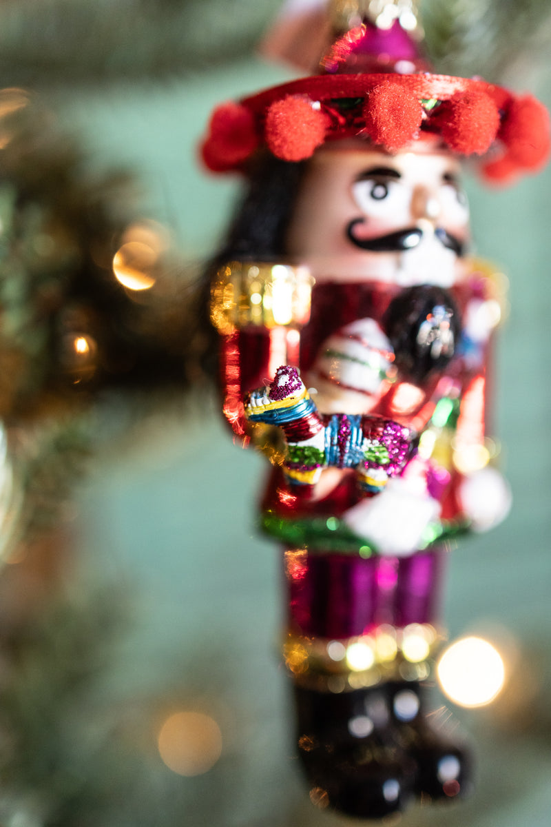 Mexican nutcracker Christmas ornament holding colorful Pinata hanging on Christmas tree