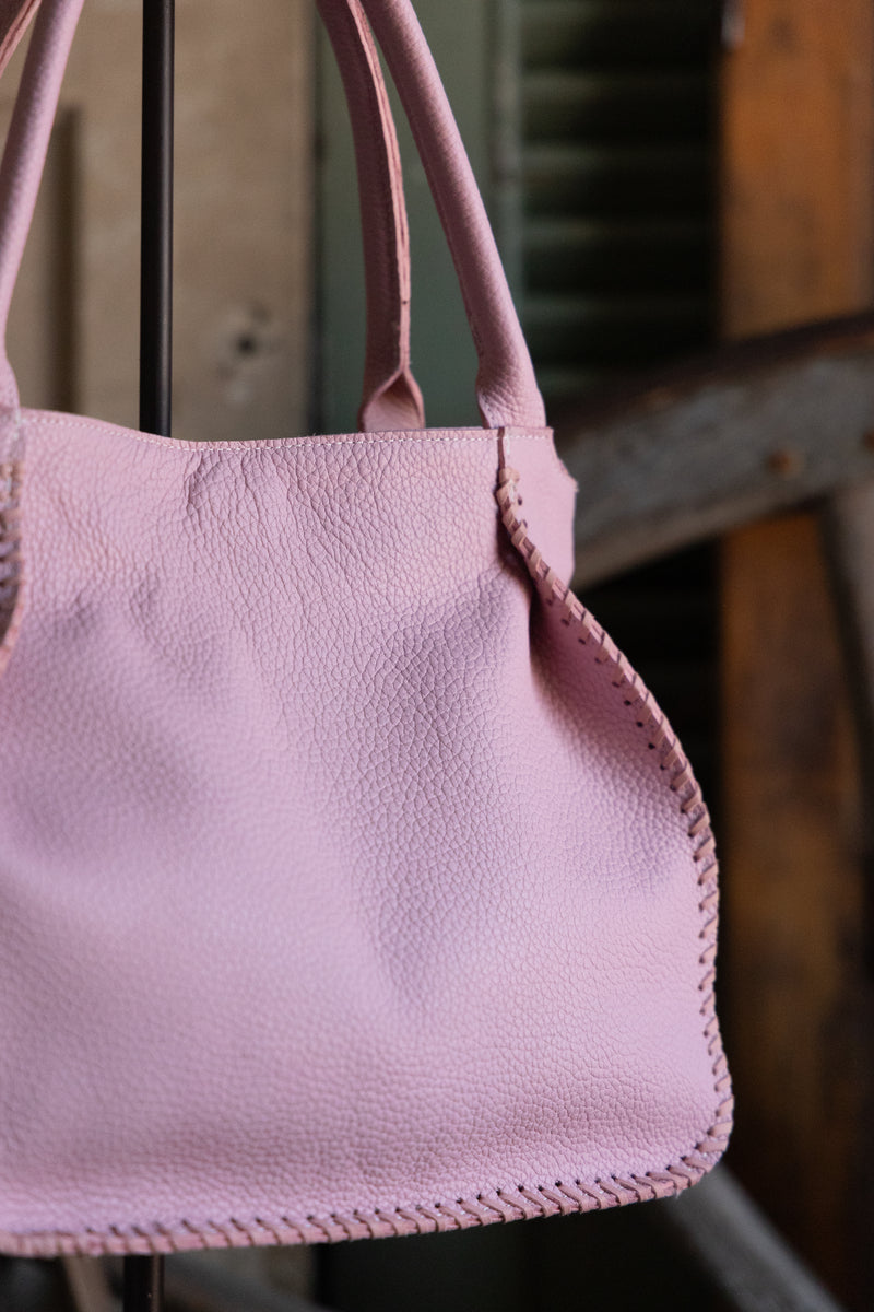 Pink handbag with a textured surface against a blurred background