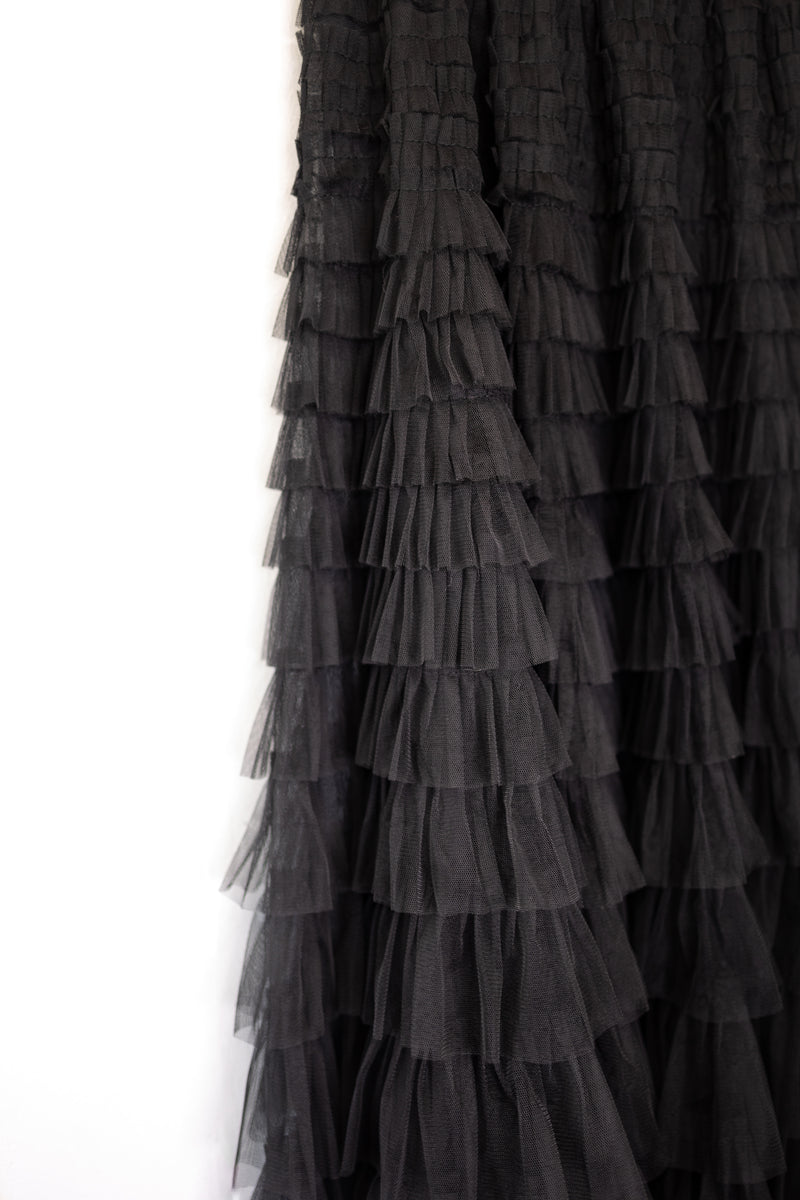 Black maxi ruffle skirt with elastic waistband on a hanger, hanging from a hook