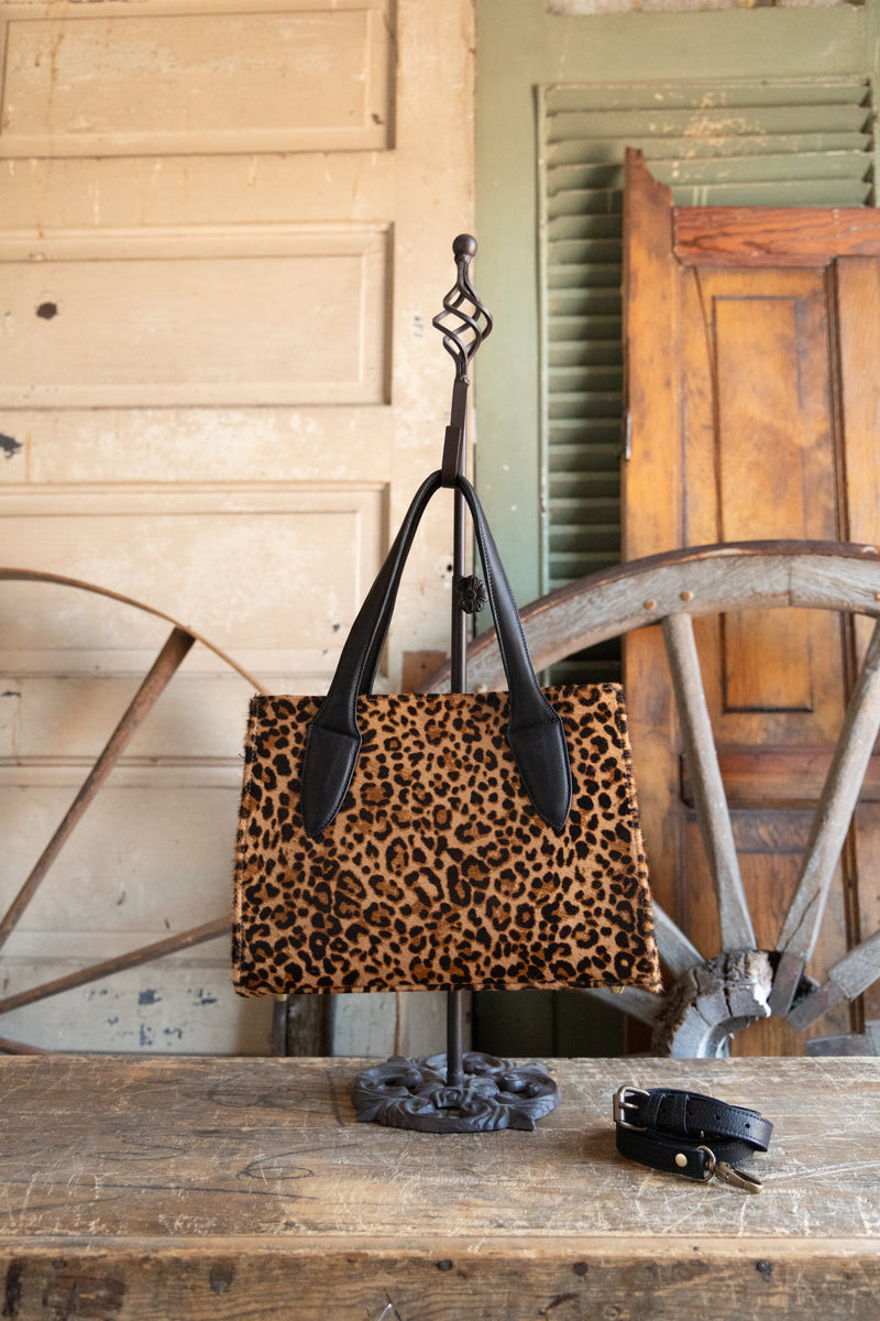 Leopard print handbag on a stand with rustic wooden background