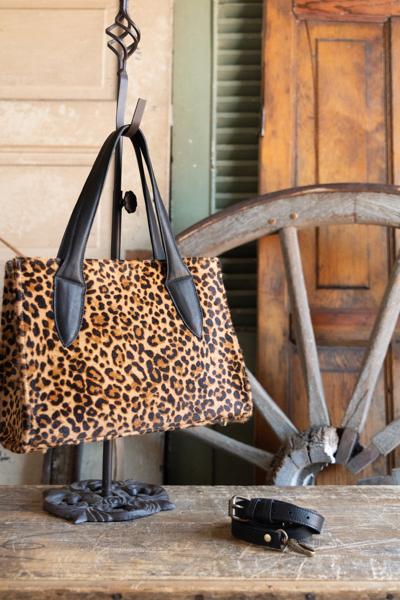 Leopard print handbag on a stand with a wooden background
