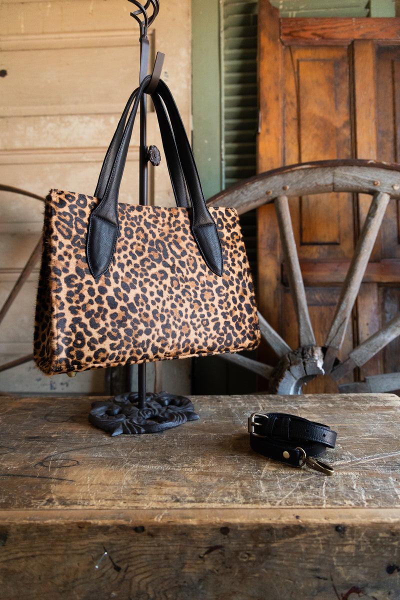 Leopard print handbag on a stand with a wooden background
