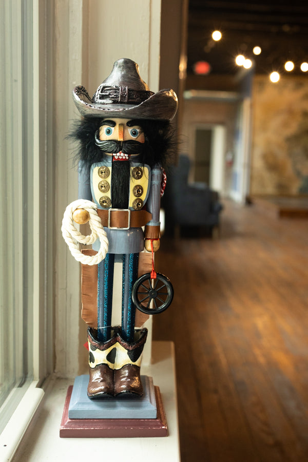 19 inch cowboy nutcracker holding a lasso and wheel