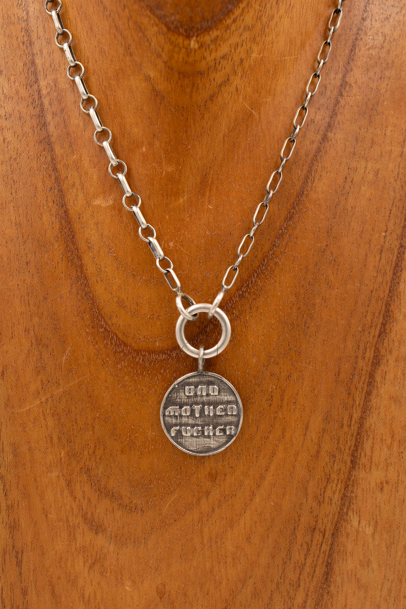 Sterling silver pendant that says "bad mother fucker" on a display necklace.