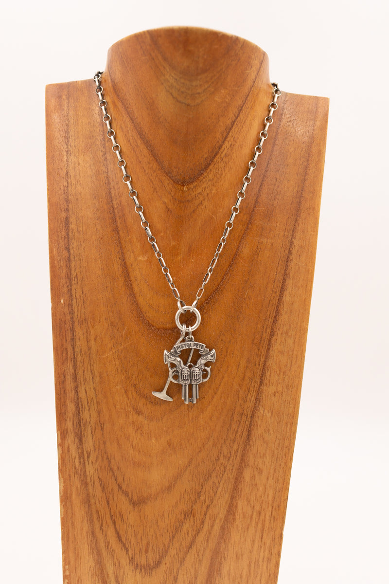 Sterling silver double gun and banner reading "pistol pete" charm on display necklace with other display charms.