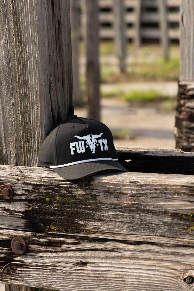 Black cap with white logo on a wooden post