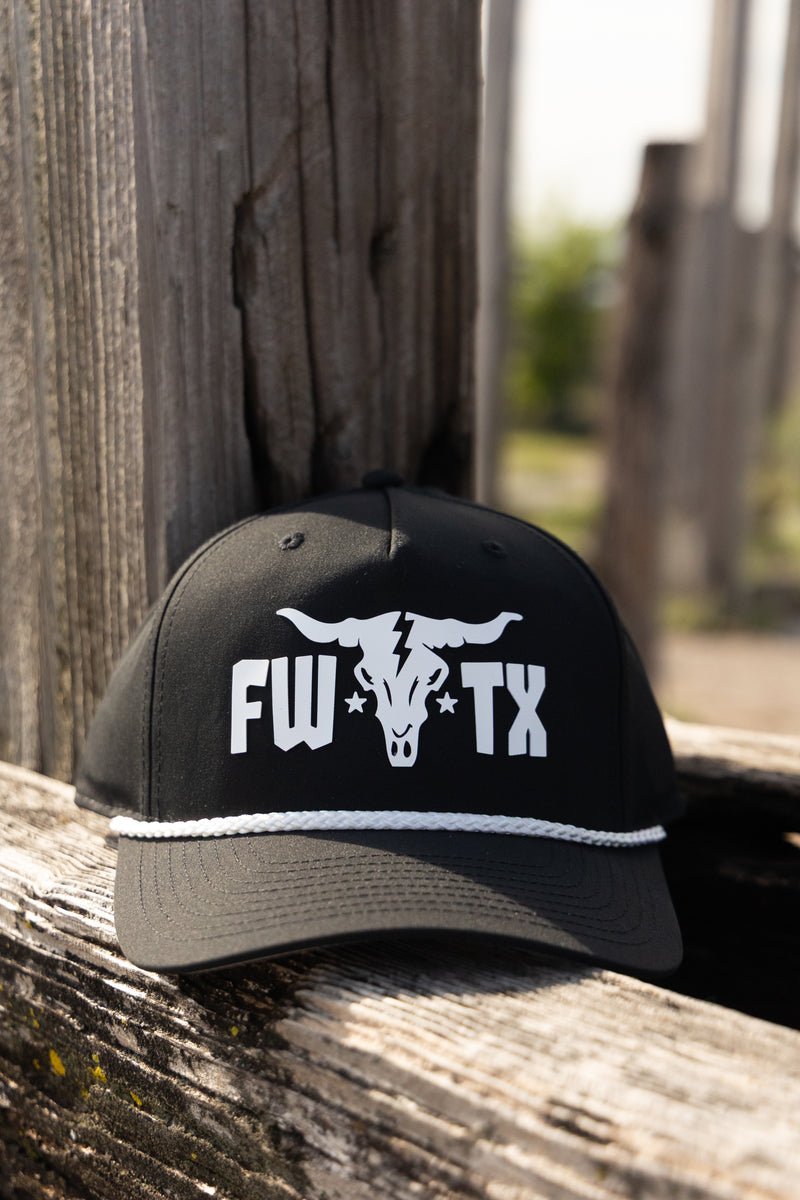 Black cap with 'FW TX' logo on a wooden surface