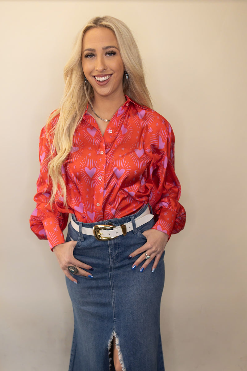 Woman wearing button up satin shirt with heart pattern all over and long puff sleeve