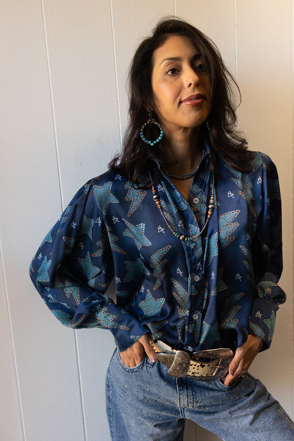 Woman wearing blue jean print pattern with stars and lightning bolts on a silk button down shirt 