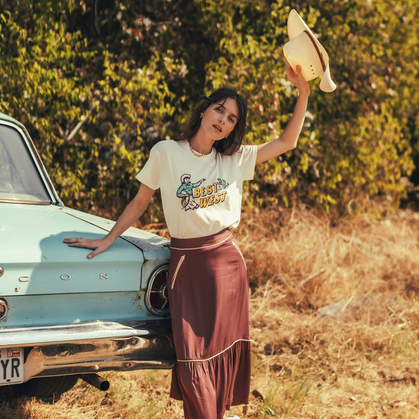 White short sleeve t-shirt in a crop top cut with image of cartoon vintage cowgirl with cactus and script "Best in the West"