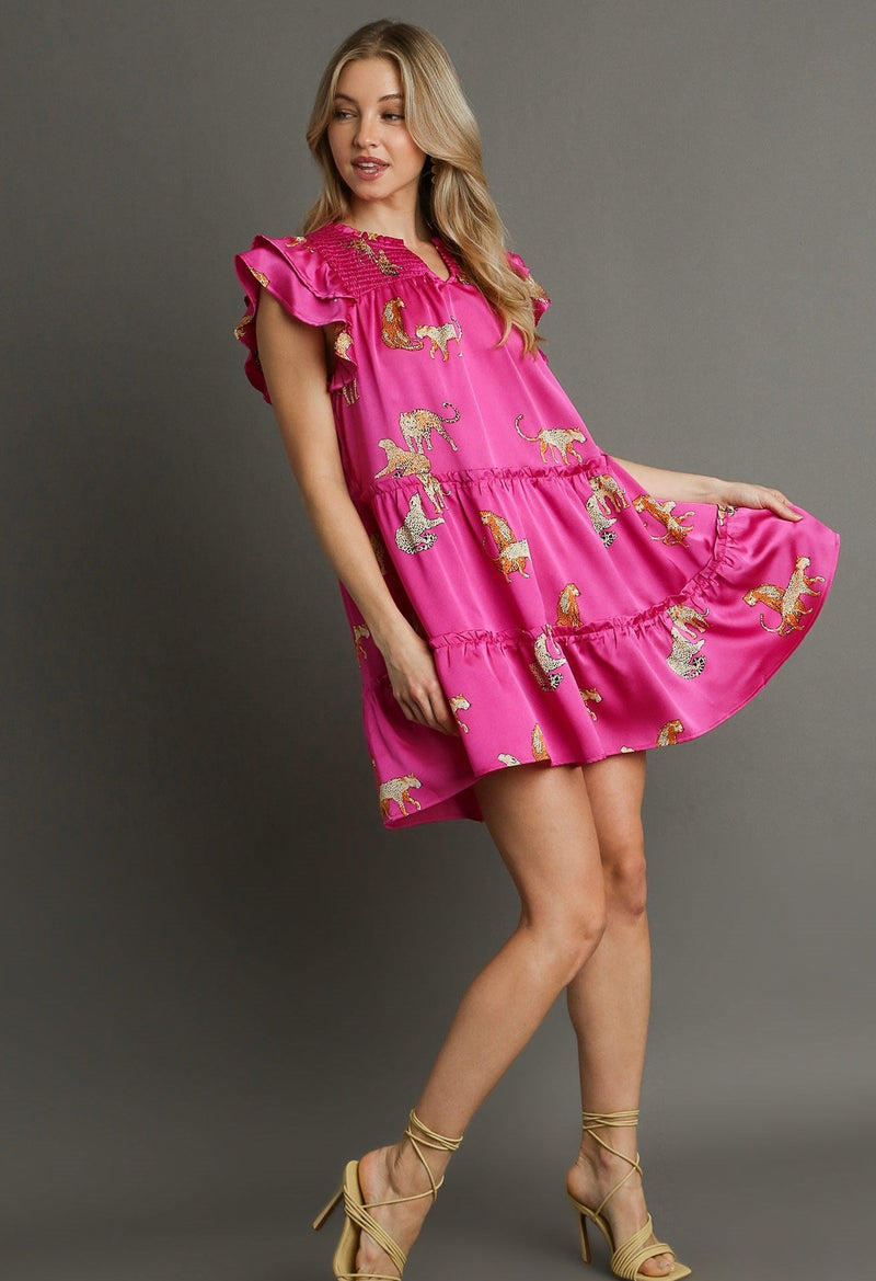 Woman wearing pink tiered dress with ruffle sleeves, vneck, and leopards all over
