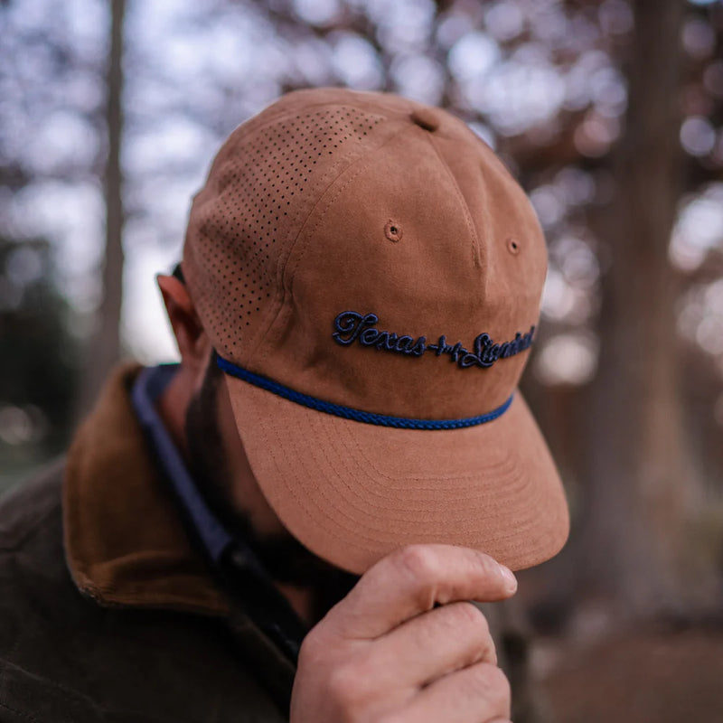 Brown cap with blue brim and embroidered text worn by a person outdoors