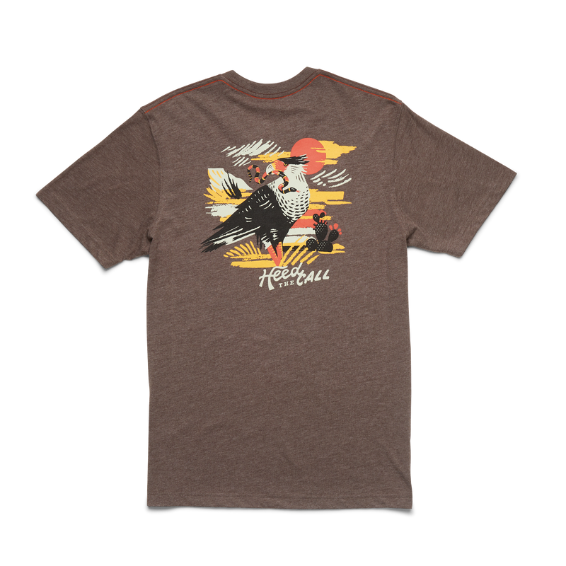 Heather brown t-shirt with graphic design on the back. Graphic design containg the image of a bird looking to its left with a snake in its mouth with the scenery of a desert in a orange, yellow, white and black color way. The bottom of the shirt contains the words "Heed the Call". 