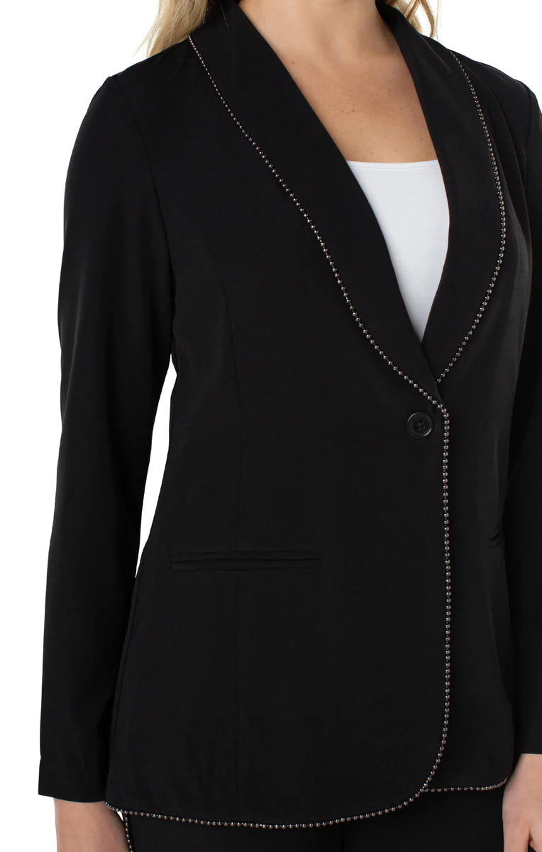 Woman wearing black blazer with chain trim