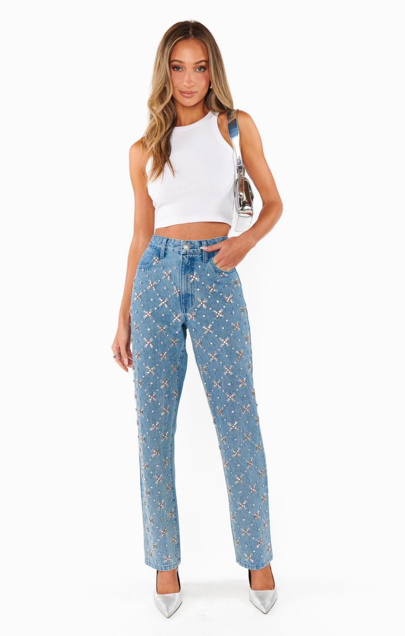 Woman wearing blue jeans with star pattern and white top on a white background