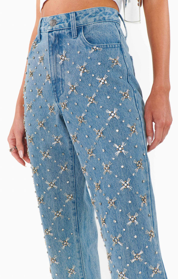 Blue jeans with decorative embellishments on a white background