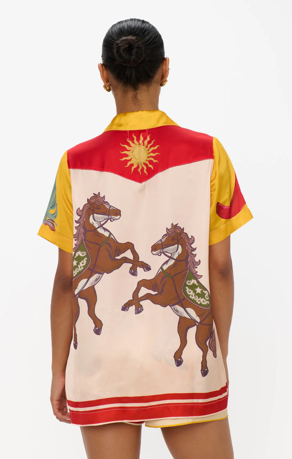 Person wearing a colorful shirt with horse designs on a plain background
