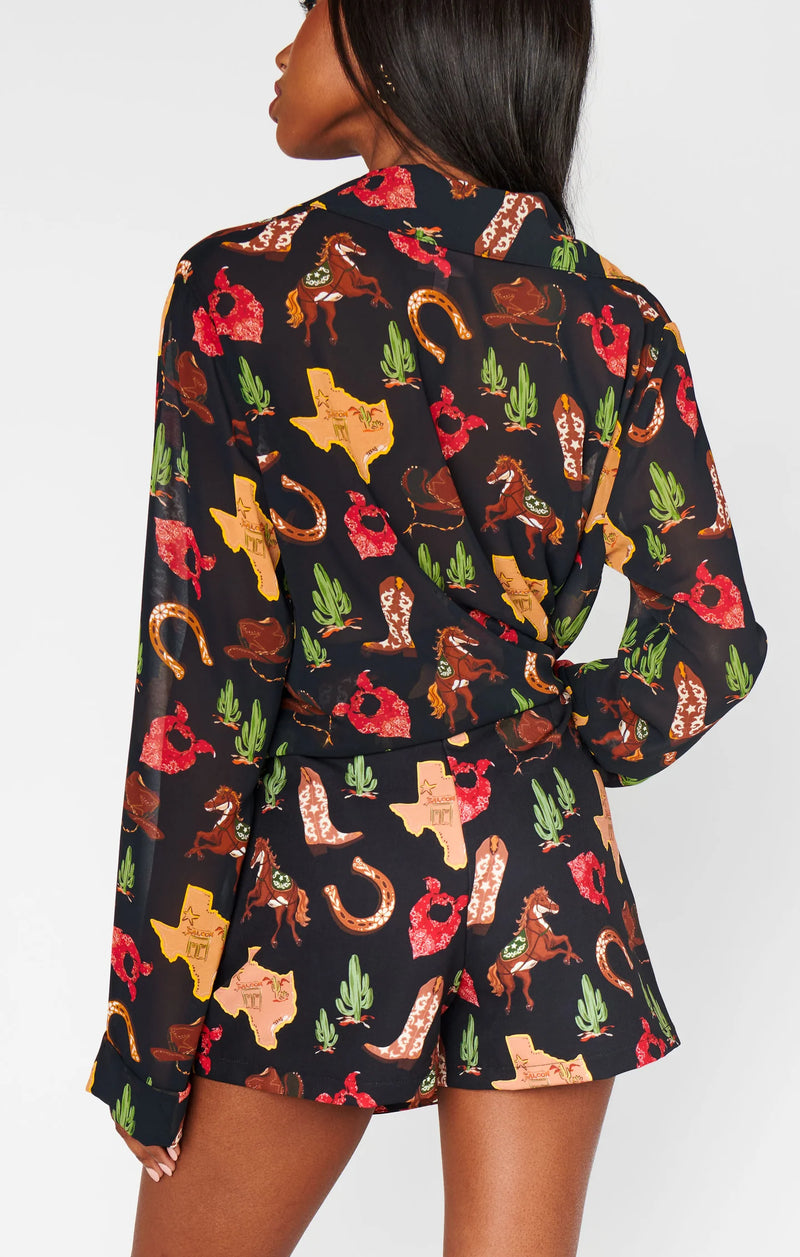 Woman wearing a dress with a colorful pattern of boots, hats, and cacti on a white background