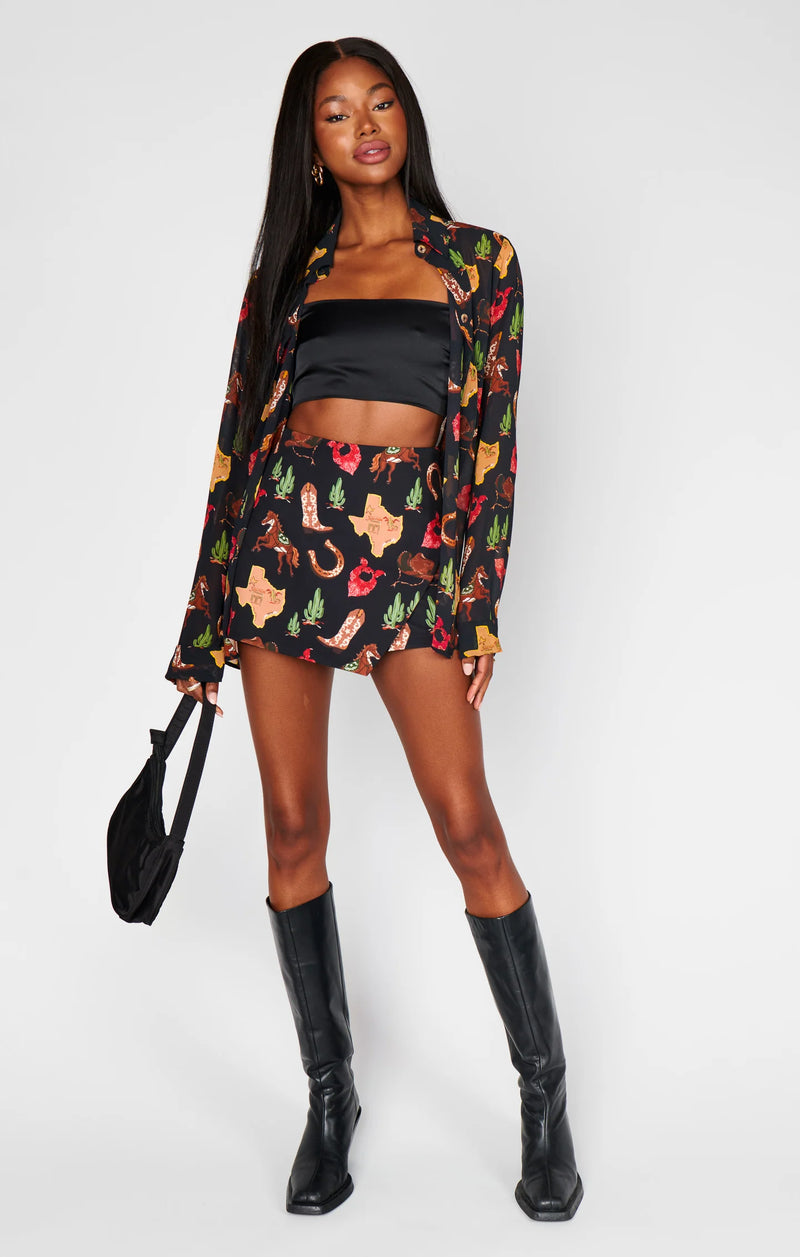 Woman wearing a colorful jacket and skirt with black boots on a white background