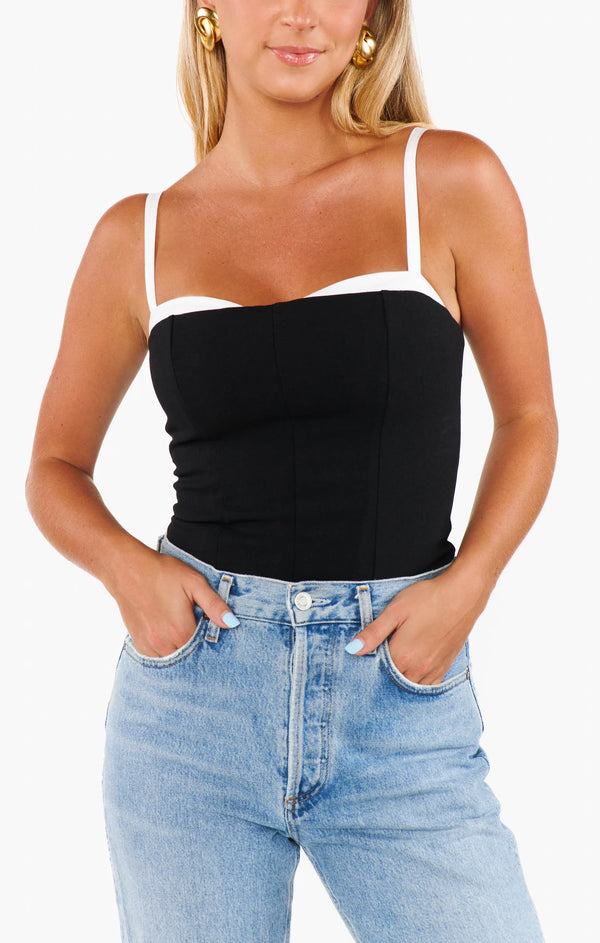 Woman wearing a black and white tank top with blue jeans on a white background