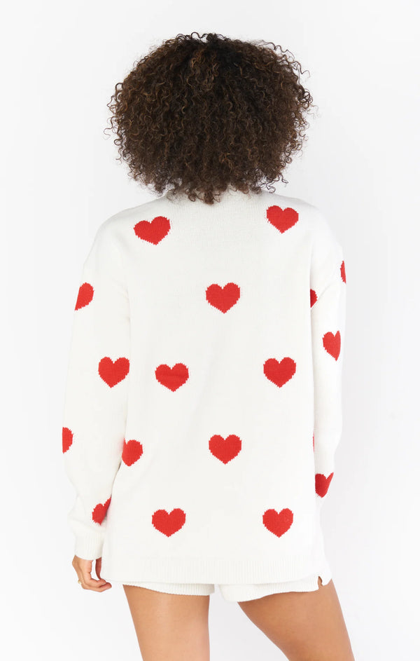 Woman wearing white sweater with red hearts all over