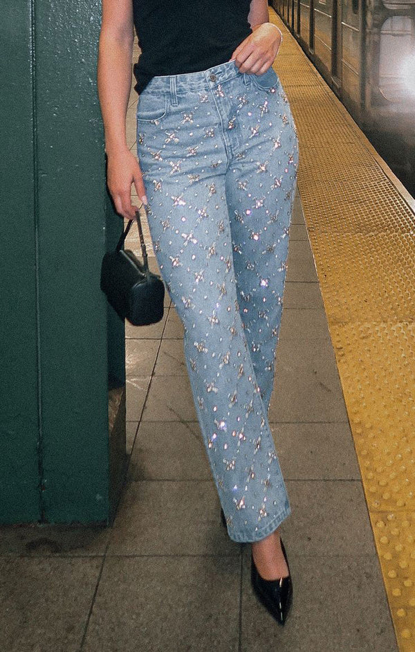 Person wearing light blue floral jeans standing on a subway platform.