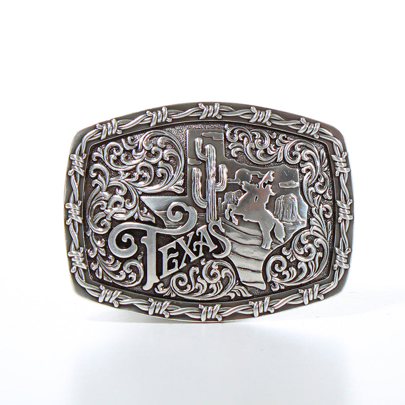 Silver belt buckle with barbed wire boarder, state of Texas with scenery of cowboy in the desert and script "Texas" next to it