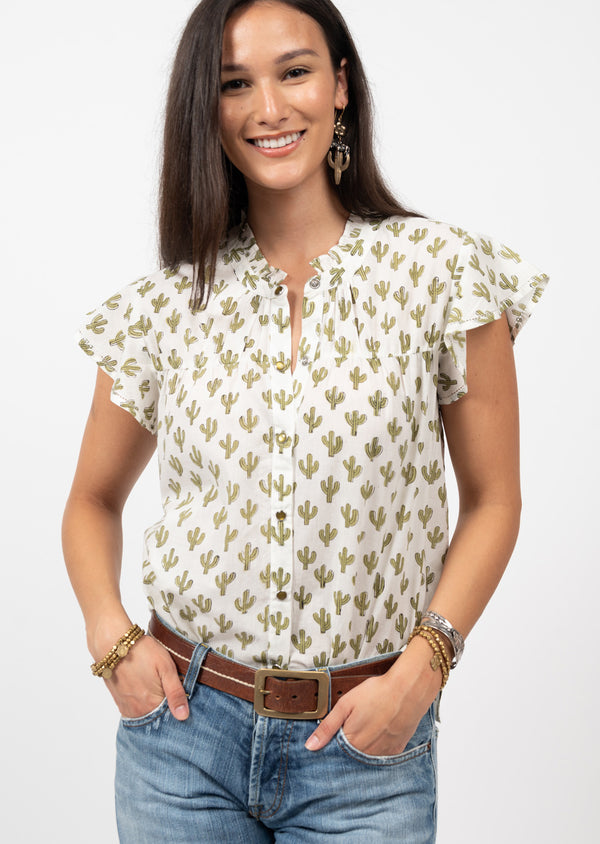 Woman wearing button up blouse with white background with green cacti all over and frilly sleeves