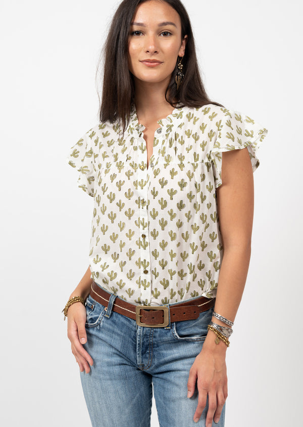 Woman wearing button up blouse with white background with green cacti all over and frilly sleeves