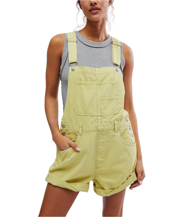 Woman wearing lime green overall shorts with pockets and crisscross cuff at the bottom