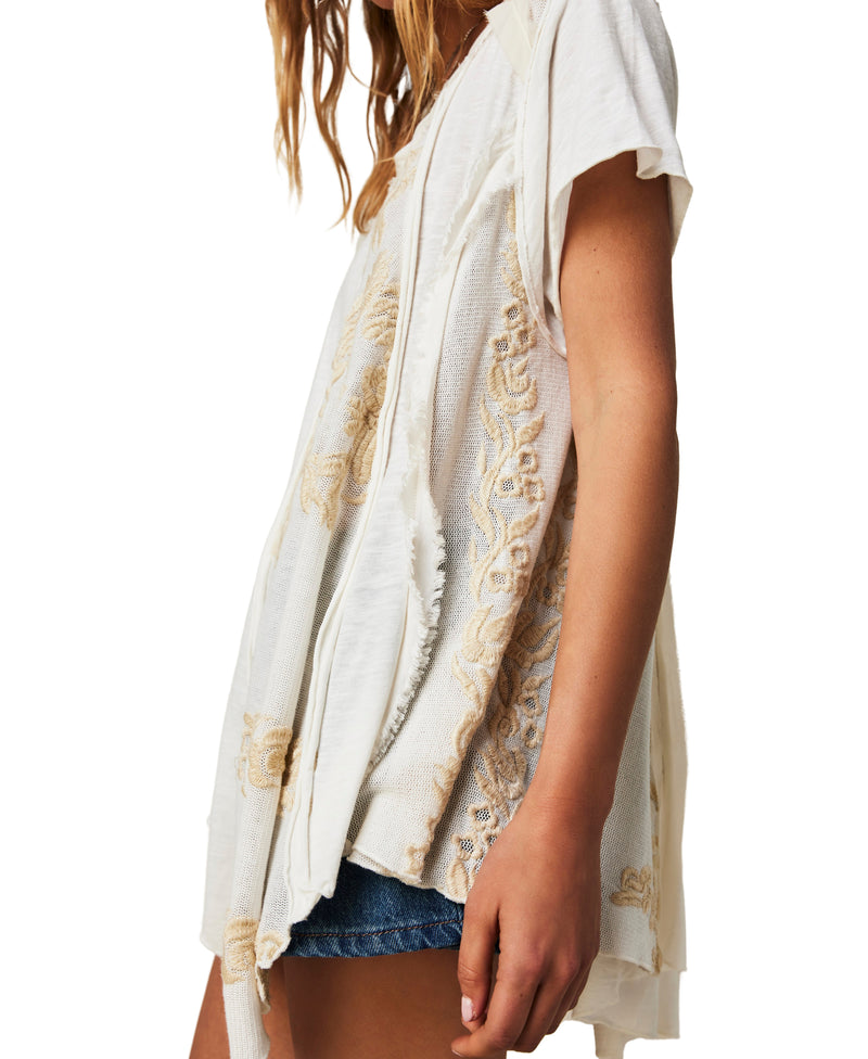 Tunic top is featured in a slouchy, relaxed fit with floral embroidery, distressed patching, and pieced fabrication for added dimension.