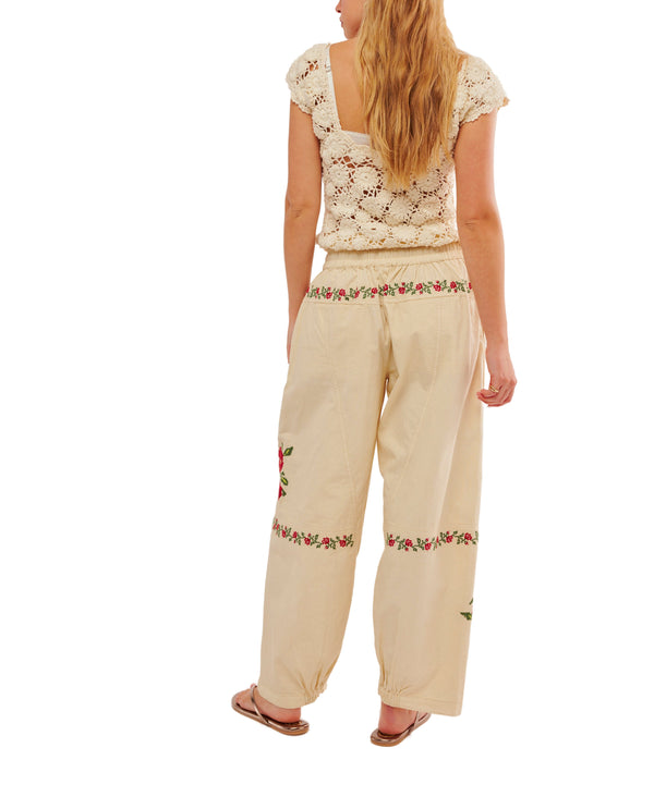 Woman wearing cream color drawstring pants with embroidered roses all over