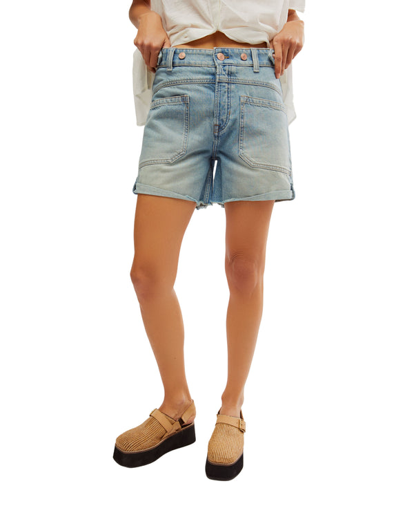 Woman wearing light wash denim shorts with wide pockets and frayed hem