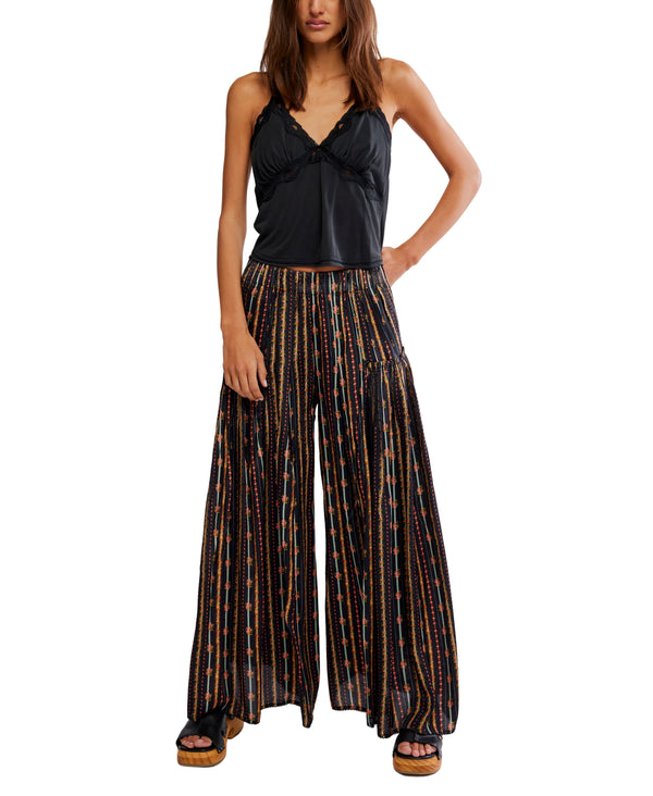 Woman wearing a black top and patterned wide-leg pants on a white background