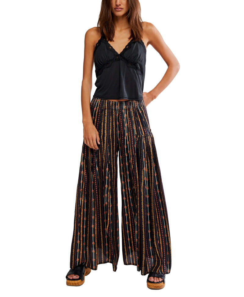 Woman wearing a black top and patterned wide-leg pants on a white background